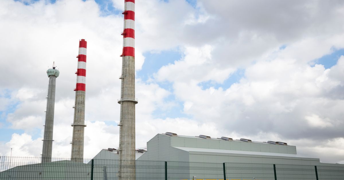 Factory chimneys against a blue sky symbolize industrial power and environmental impact.